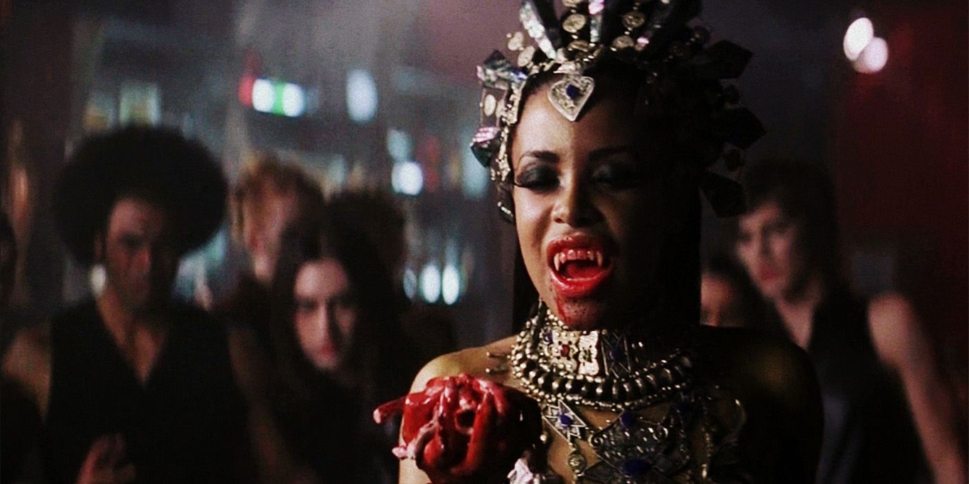 Aaliyah showing vampire fangs and holding a bleeding heart in Queen of the Damned