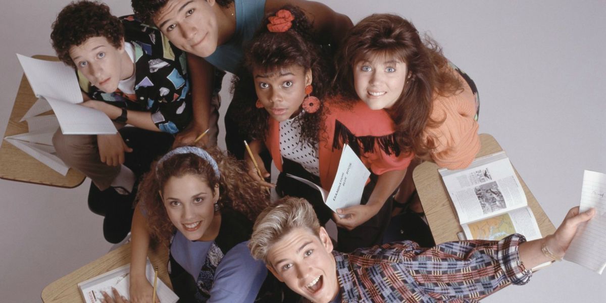 Saved by the Bell cast sat together at a desk while looking up