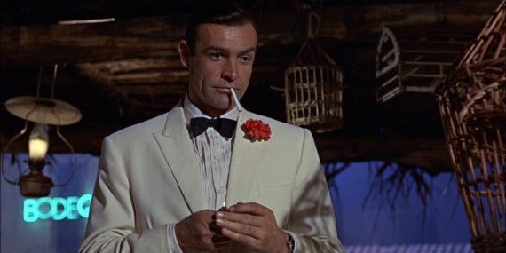 Sean Connery as James Bond in Goldfinger, wearing a white suit and about to light a cigarette