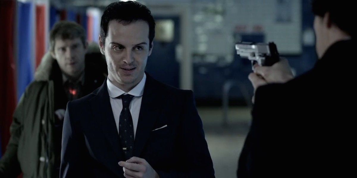 Sherlock pointing a gun at a smirking Moriarty in Sherlock.