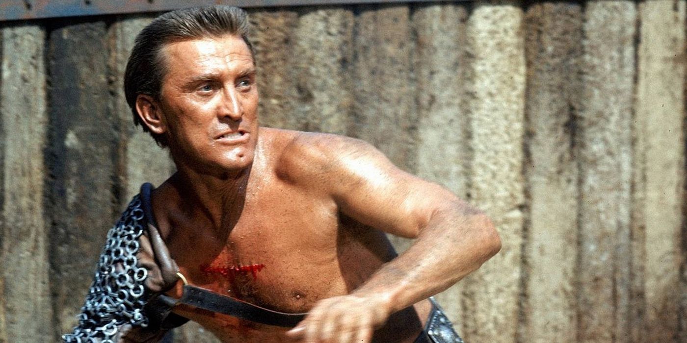 A closeup of a shirtless Kirk Douglas with one chainmail covered arm preparing to fight in Spartacus