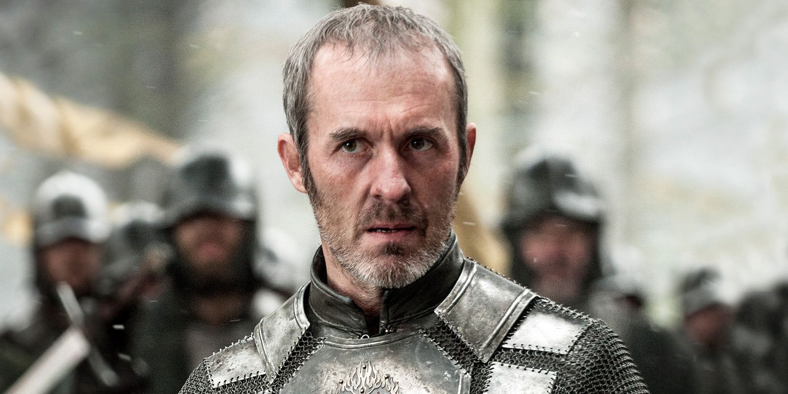 Stannis Baratheon looking serious while his army stands behind him in Game of Thrones.