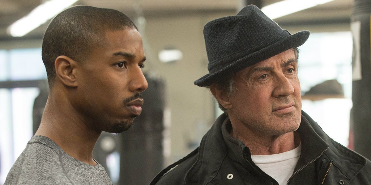Sylvester Stallone as Rocky Balboa stands next to Creed in the gym In Creed