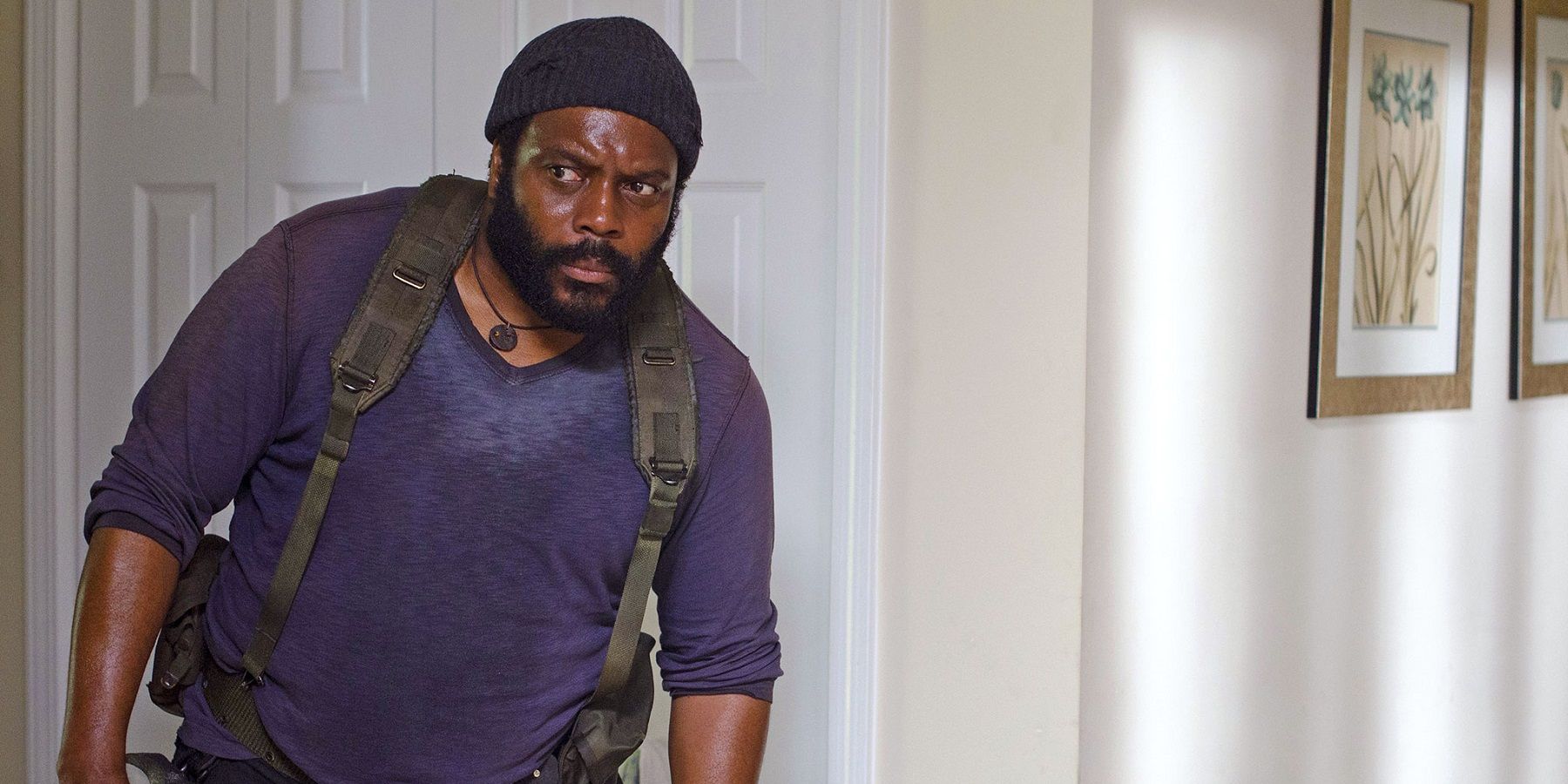 Tyreese in The Walking Dead, peeking around a corner, a backpack on.