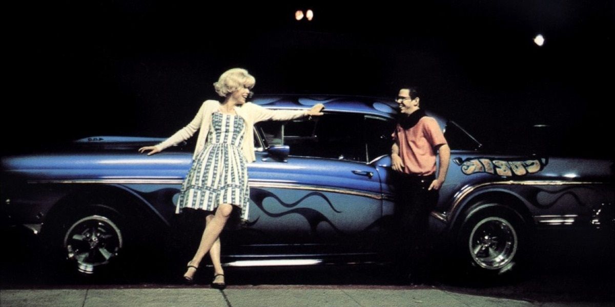 A guy and a girl by a car in American Graffiti