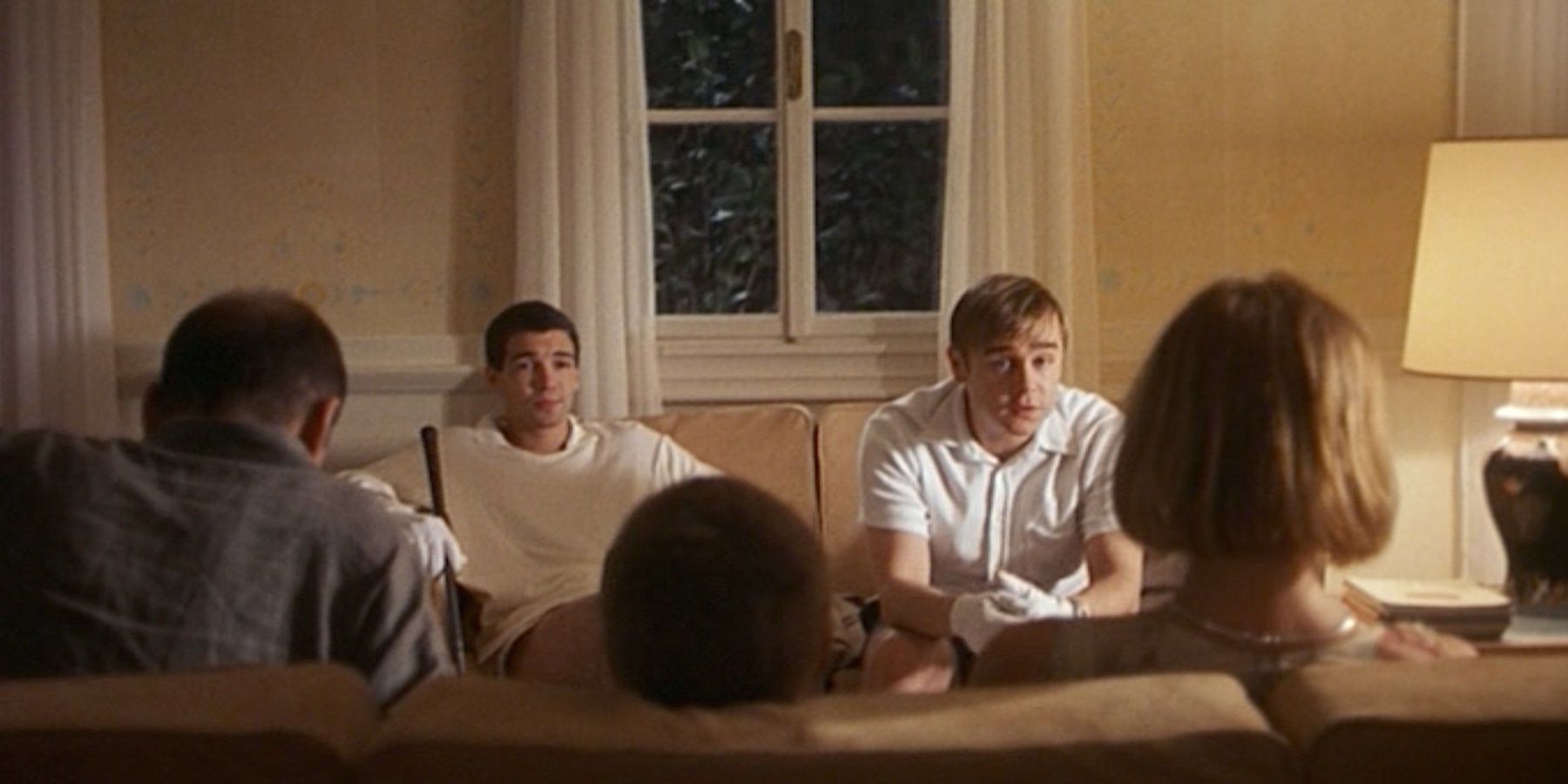 Peter and Paul sitting with the family in their house in Funny Games