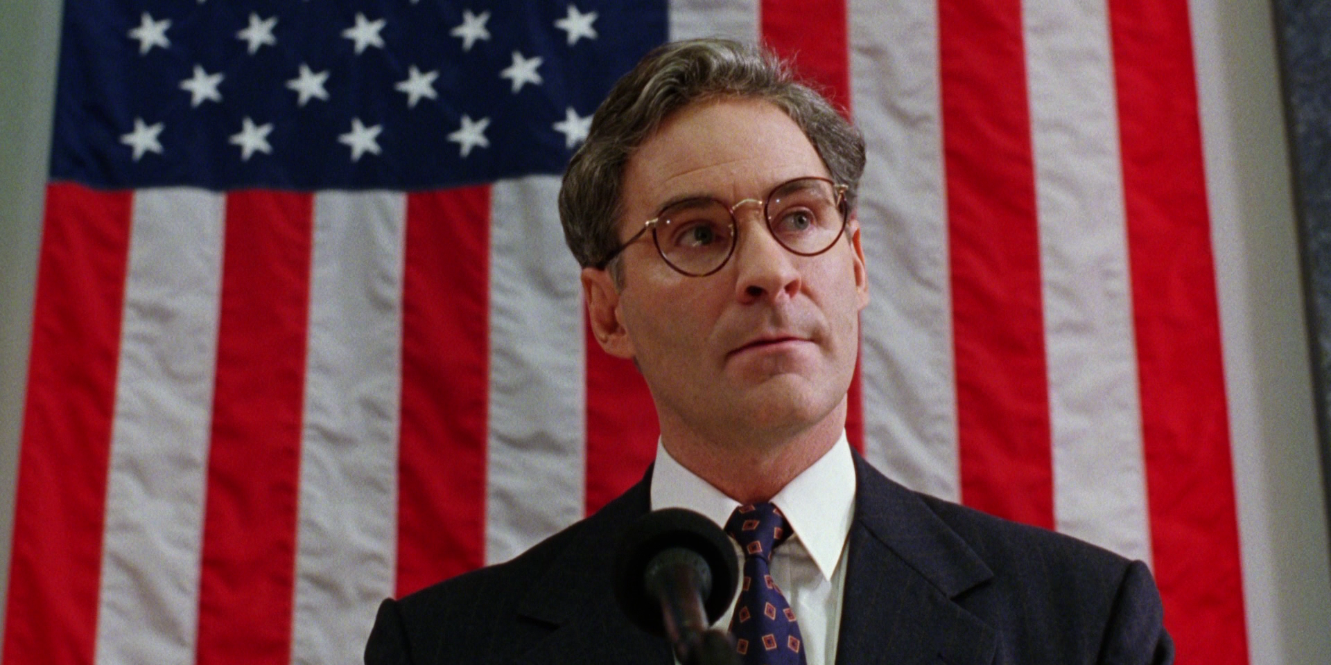 Kevin Kline stands in front of American flag in Dave - Movie Presidents