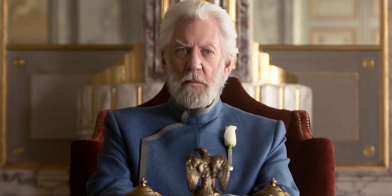 President Snow frowning while sitting behind a desk in The Hunger Games