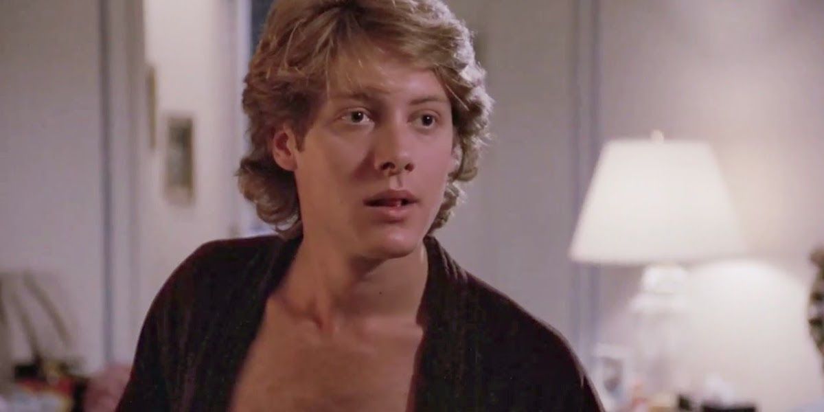 James Spader in a scene from Pretty in Pink, wearing a robe and no shirt, blonde hair long and swept.