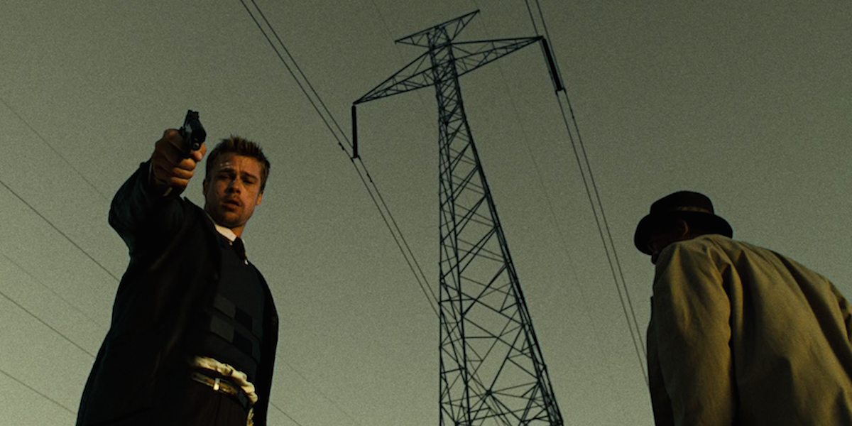 Brad Pitt's character pointing a gun towards the ground in Se7en