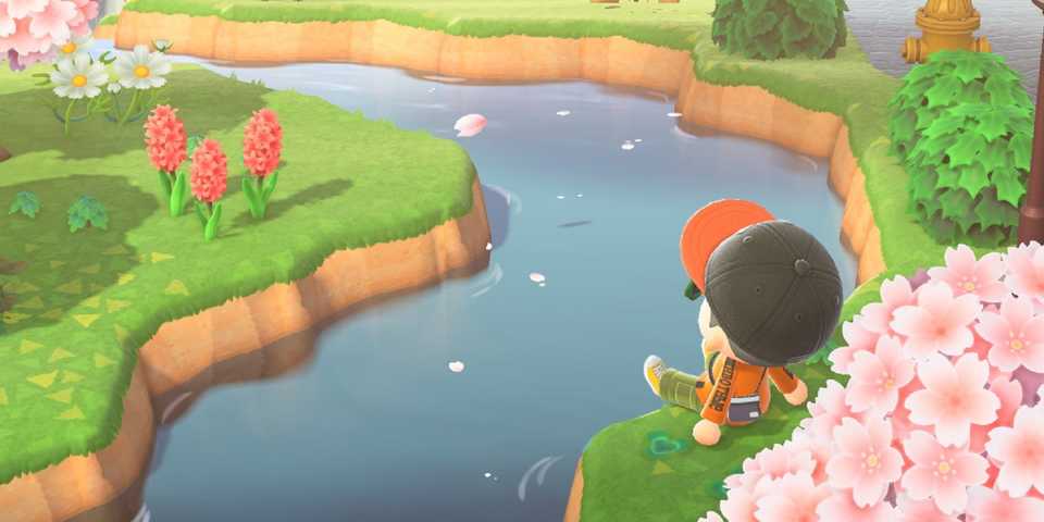 A player character sitting at the bank of the river in Animal Crossing New Horizons