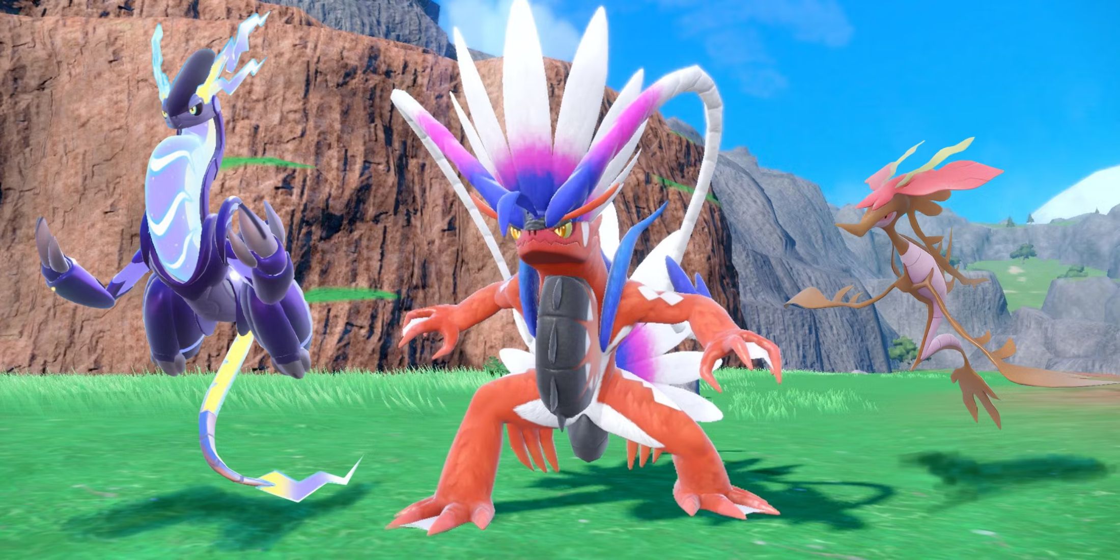 The Pokemon Scarlet and Violet legendaries, Koraidon, Miraidon, and Dragalge in a row in a grassy field.