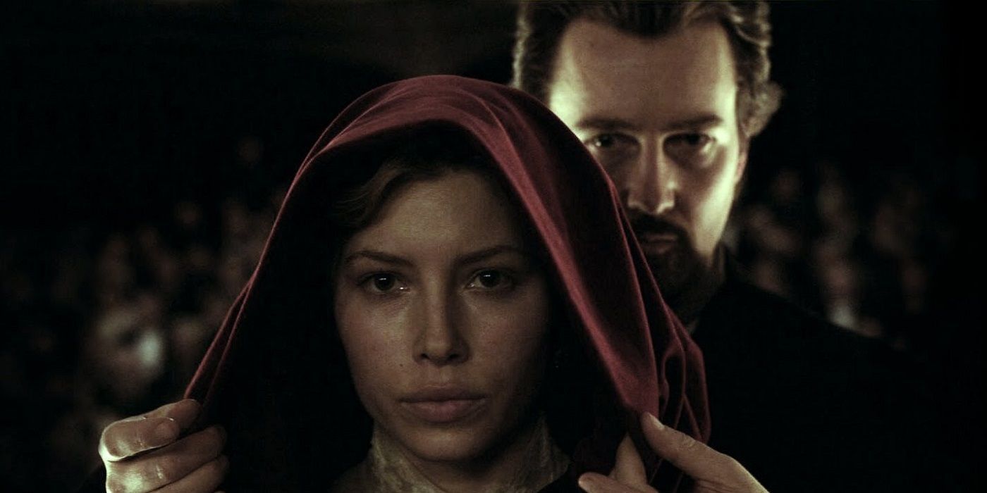 Edward Norton standing behind Jessica Biel, about to peel back her hood in The Illusionist