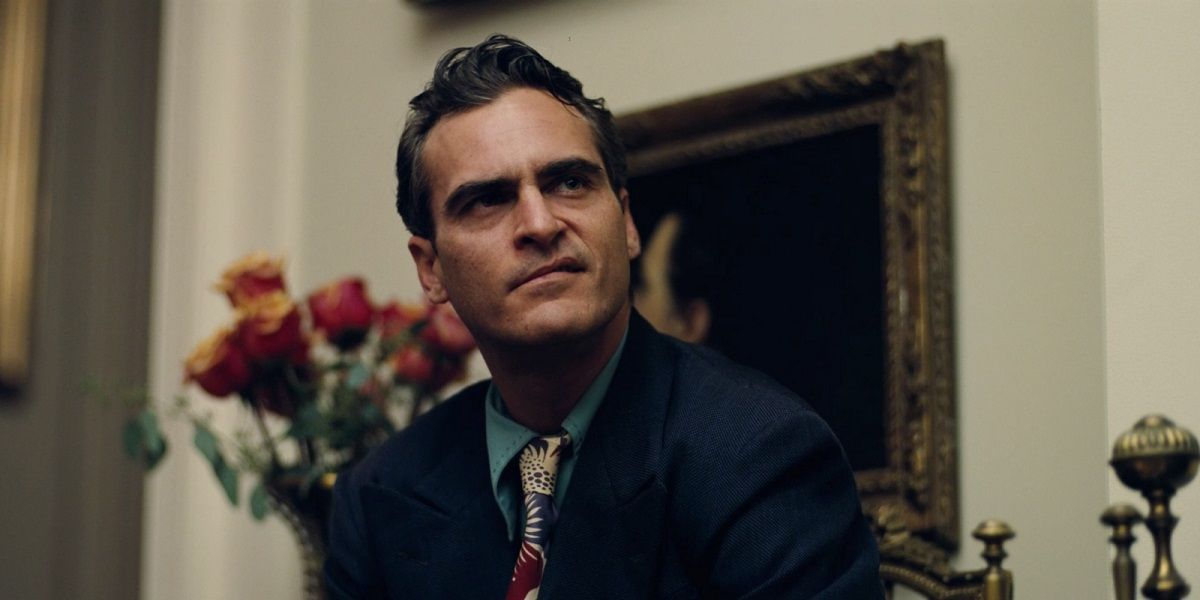 Joaquin Phoenix sitting in front of a painting in The Master