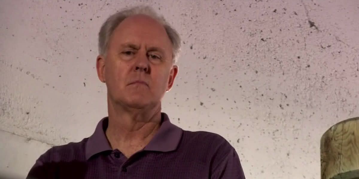 John Lithgow as Trinity Killer, looking down ominously at someone.