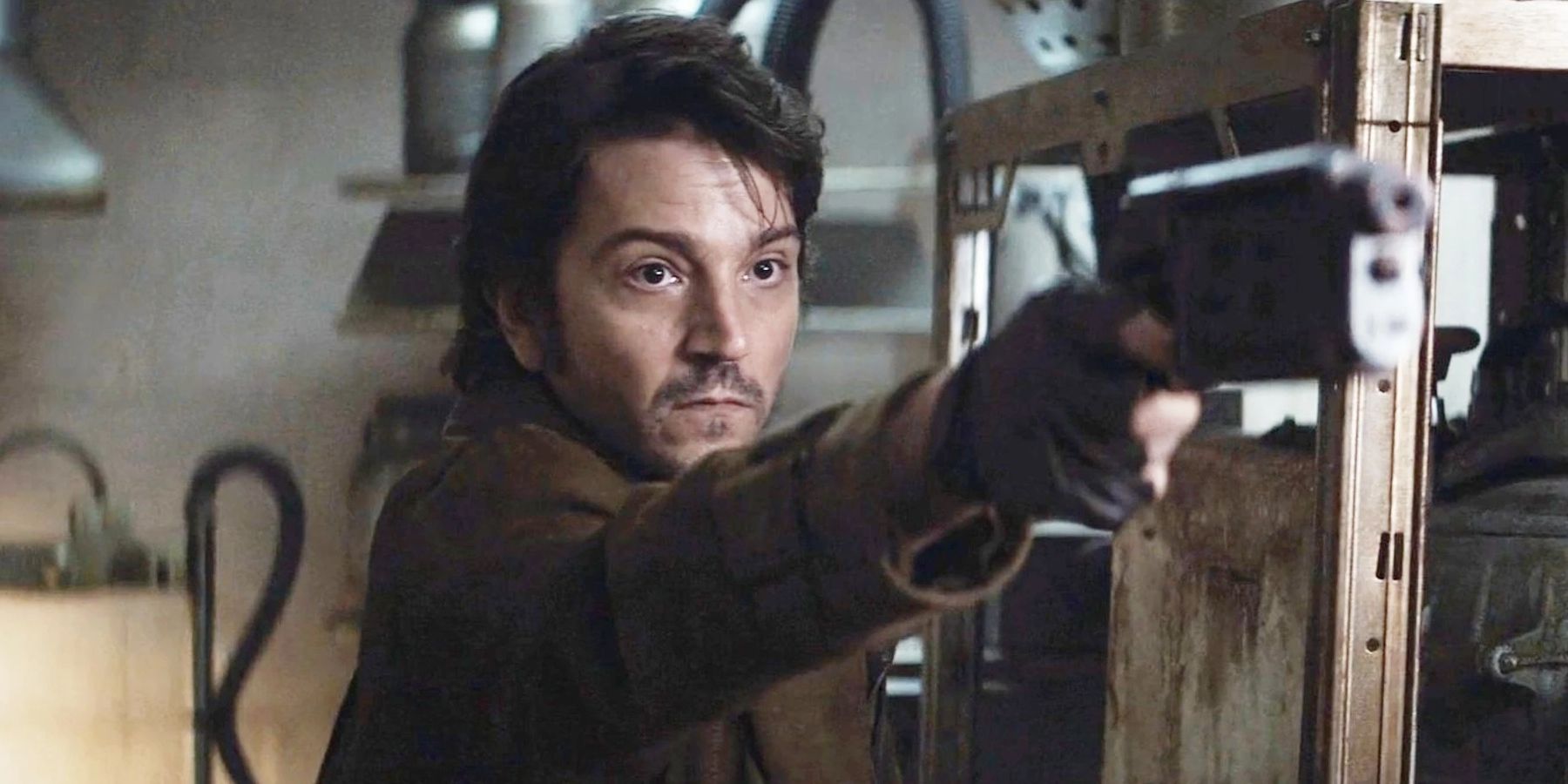 Diego Luna as Cassian Andor pointing a blaster gun weapon in Star Wars Andor with a serious look on his face