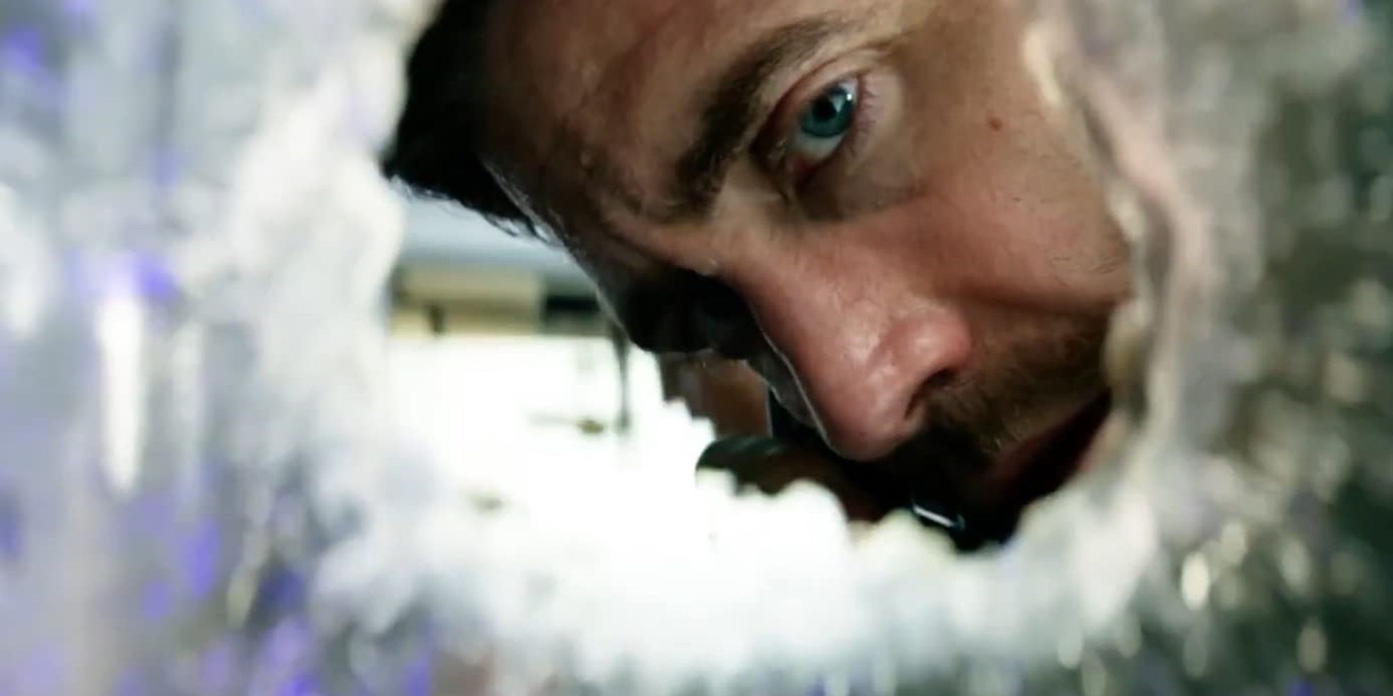 Jake Gyllenhaal looking through a broken window in Ambulance